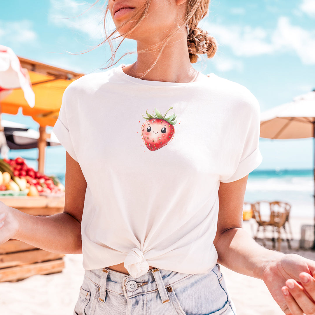 a woman standing on a beach with a strawberries t - shirt on