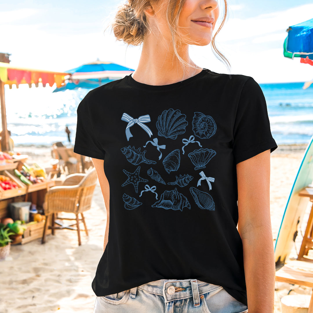 a woman standing on a beach wearing a black shirt