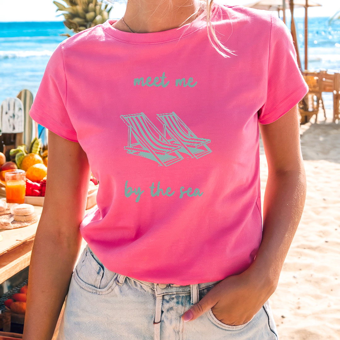 a woman in a pink shirt standing on a beach