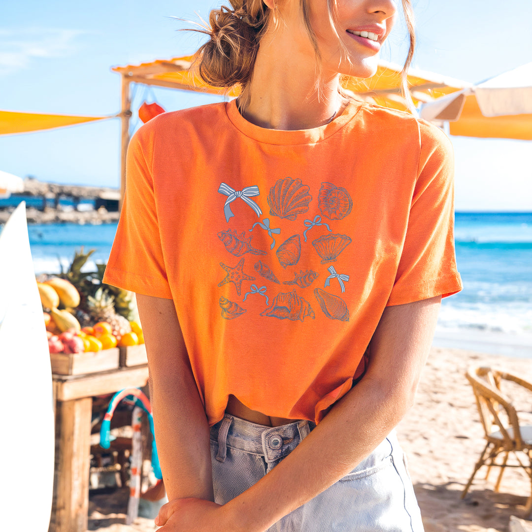 a woman in an orange shirt standing on a beach