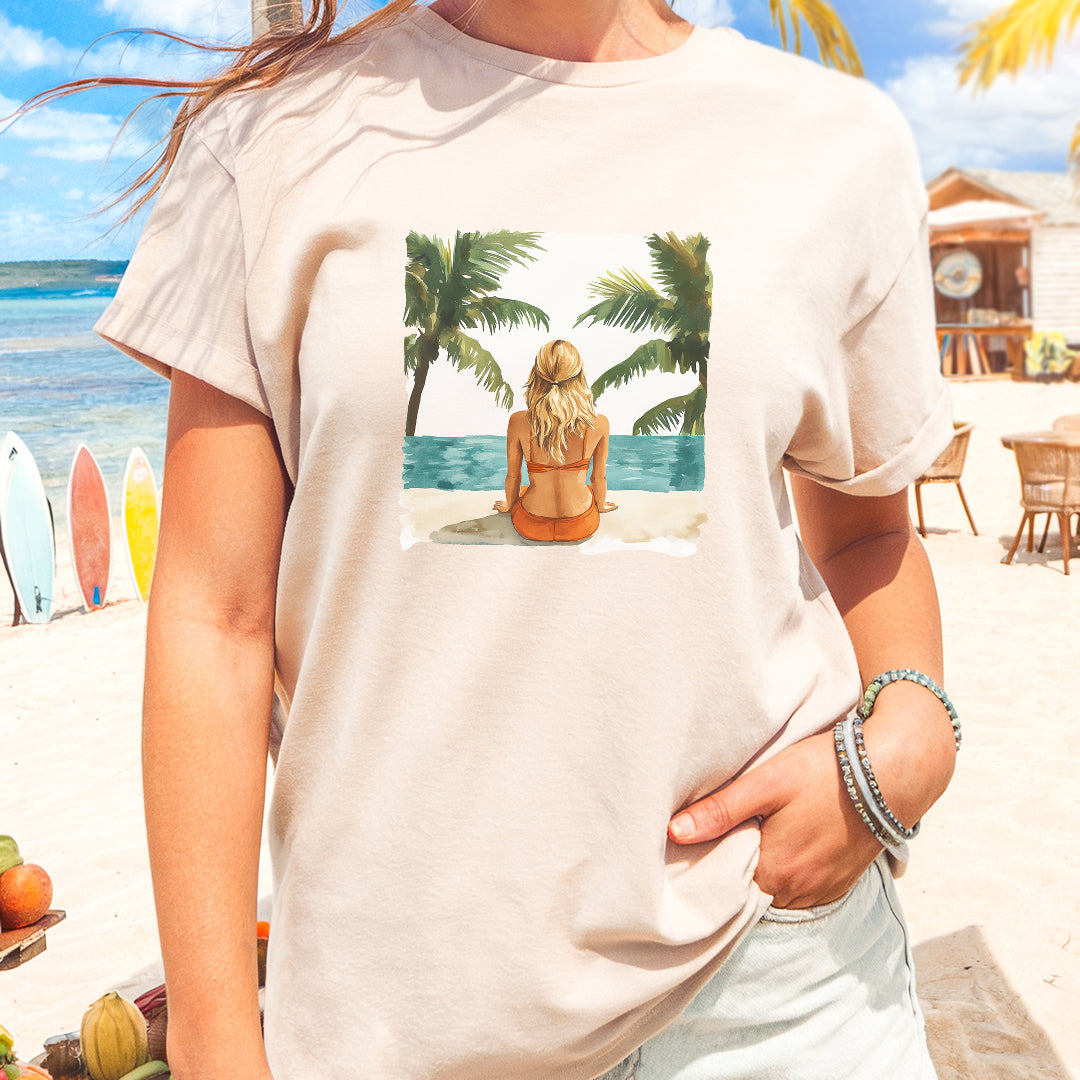 a woman standing on a beach wearing a t - shirt with a picture of a