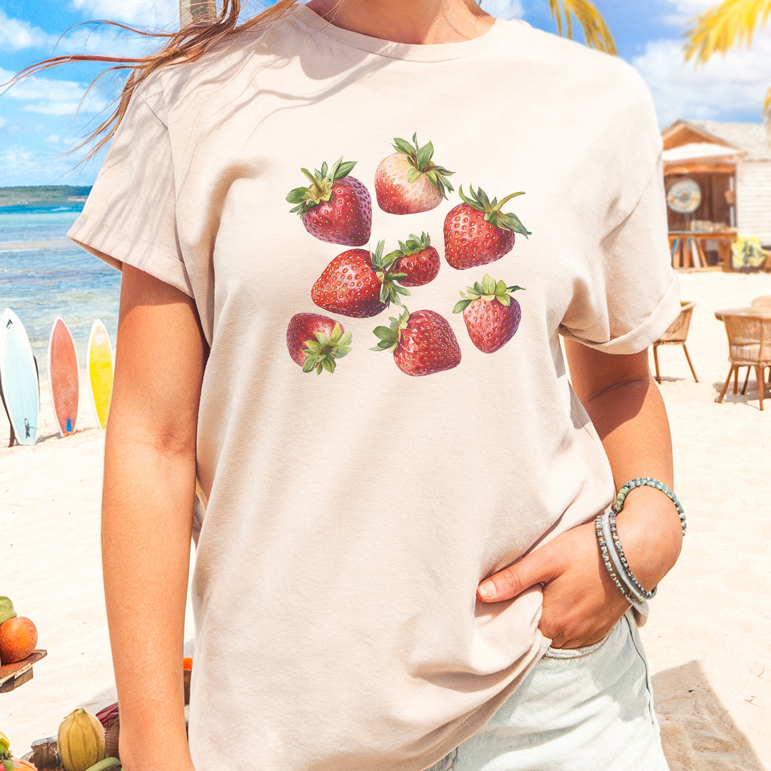 a woman standing on a beach with strawberries on her shirt