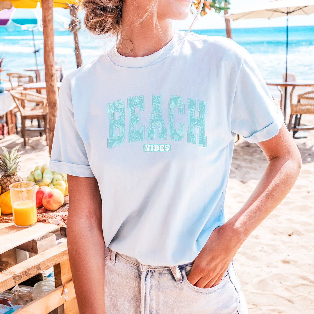 a woman wearing a beach vibes t - shirt on the beach
