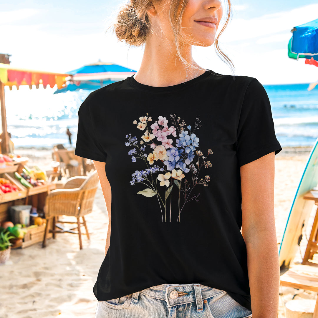 a woman standing on a beach wearing a t - shirt with flowers on it