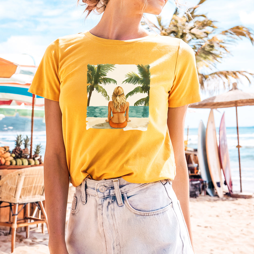 a woman standing on a beach wearing a t - shirt with a picture of a
