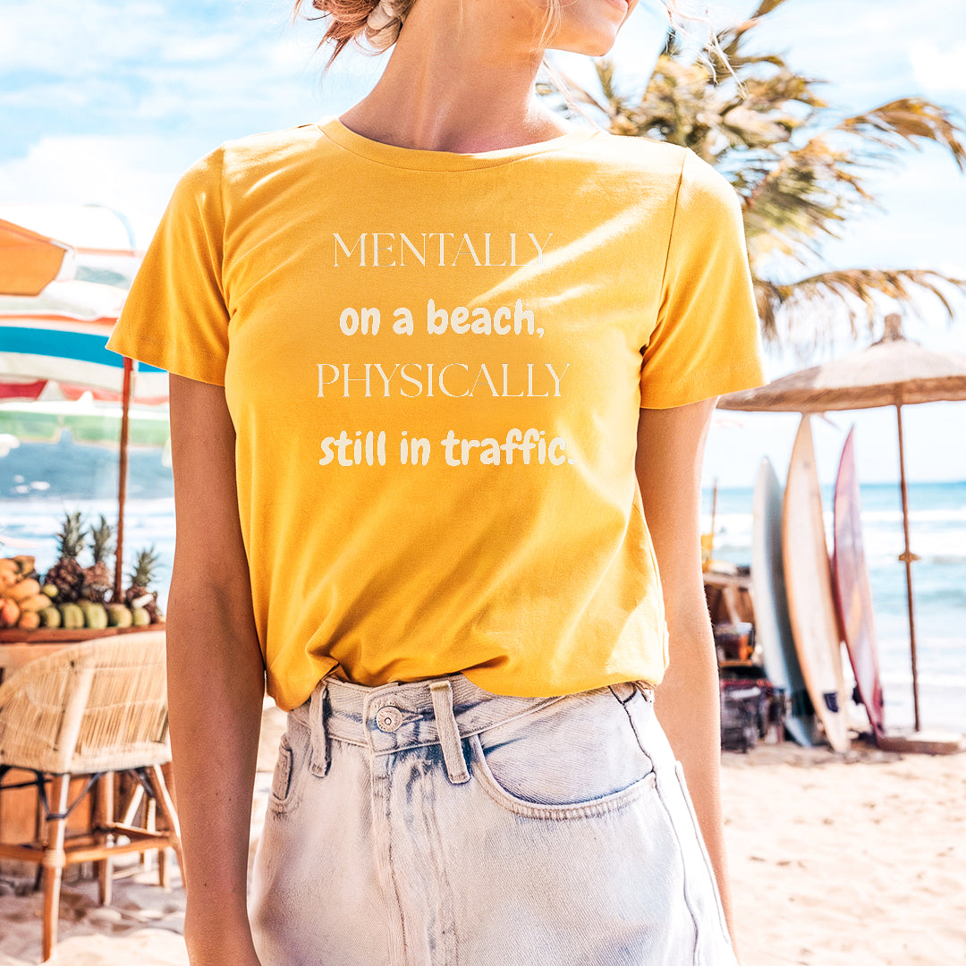 a woman standing on a beach wearing a yellow shirt