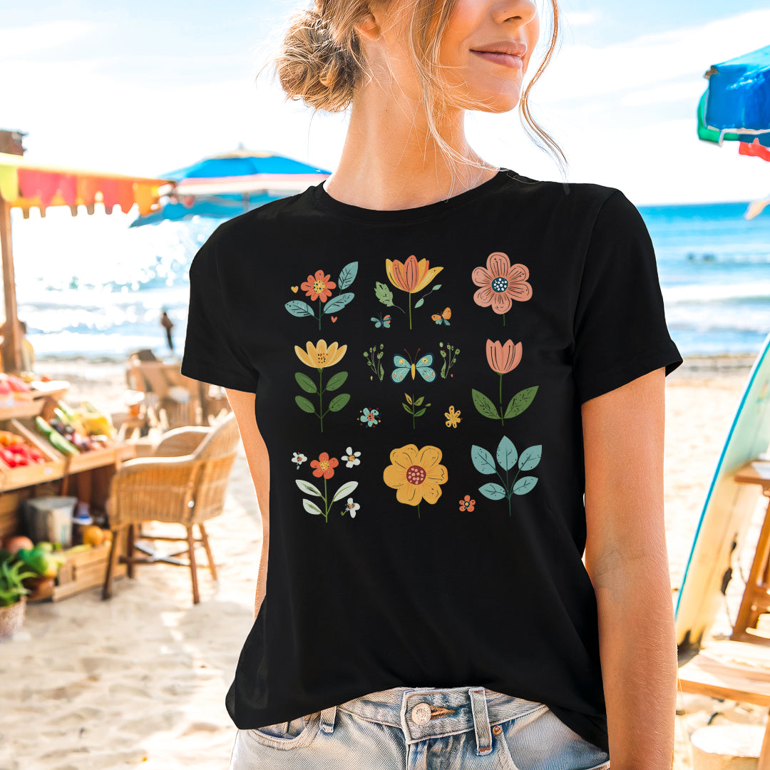 a woman standing on a beach wearing a t - shirt with flowers on it