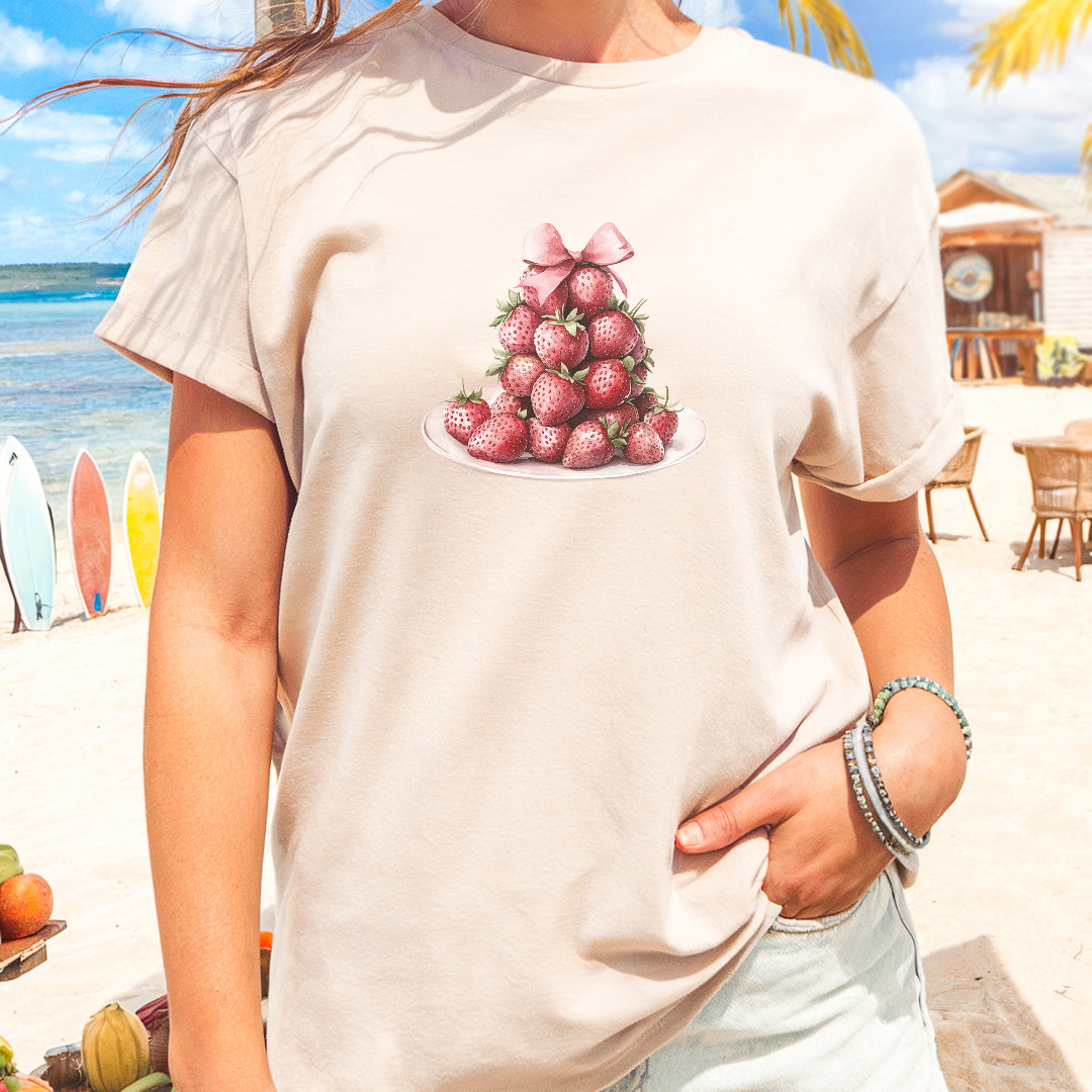 a woman standing on a beach with strawberries on a plate