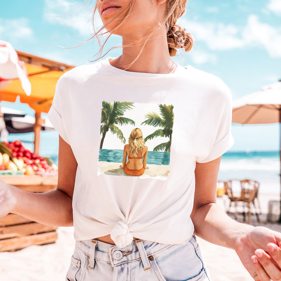 a woman wearing a white shirt with a picture of a woman sitting on a beach