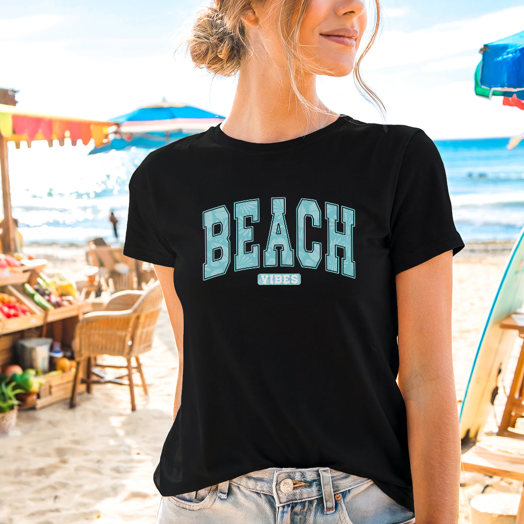 a woman standing on the beach wearing a black shirt