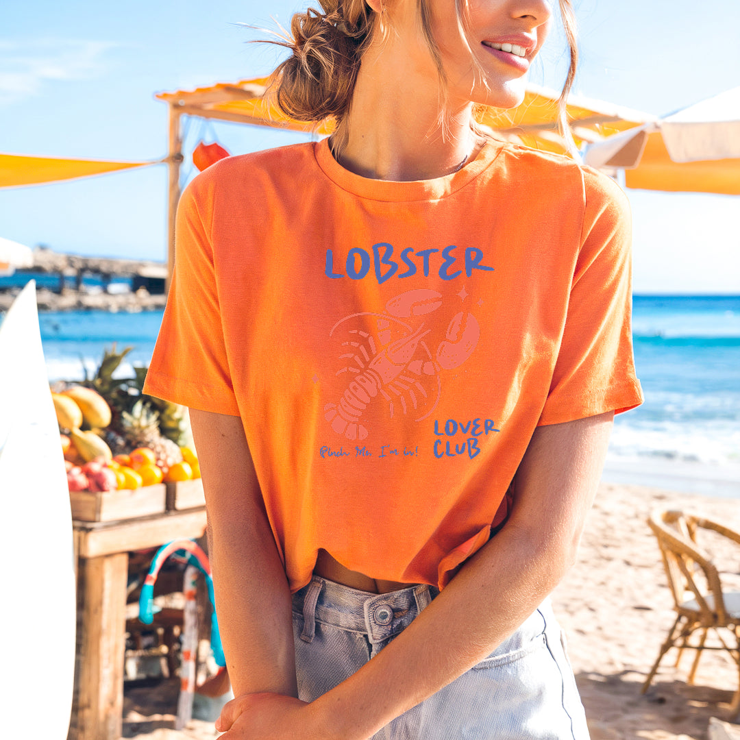 a woman in an orange shirt standing on a beach