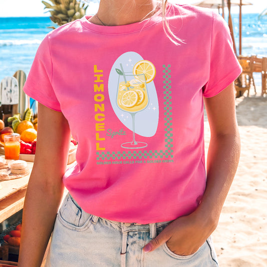 a woman standing on a beach wearing a pink shirt