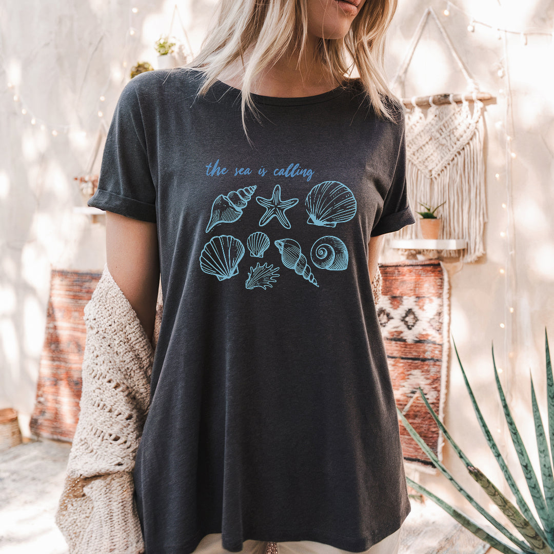 a woman wearing a t - shirt that says the sea is calling