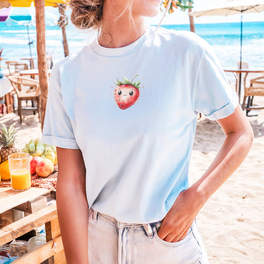 a woman standing on a beach with a strawberries t - shirt on