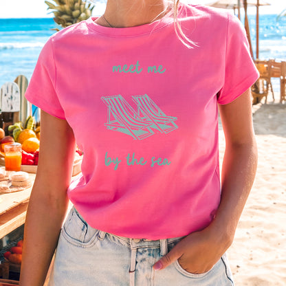 a woman in a pink shirt standing on a beach