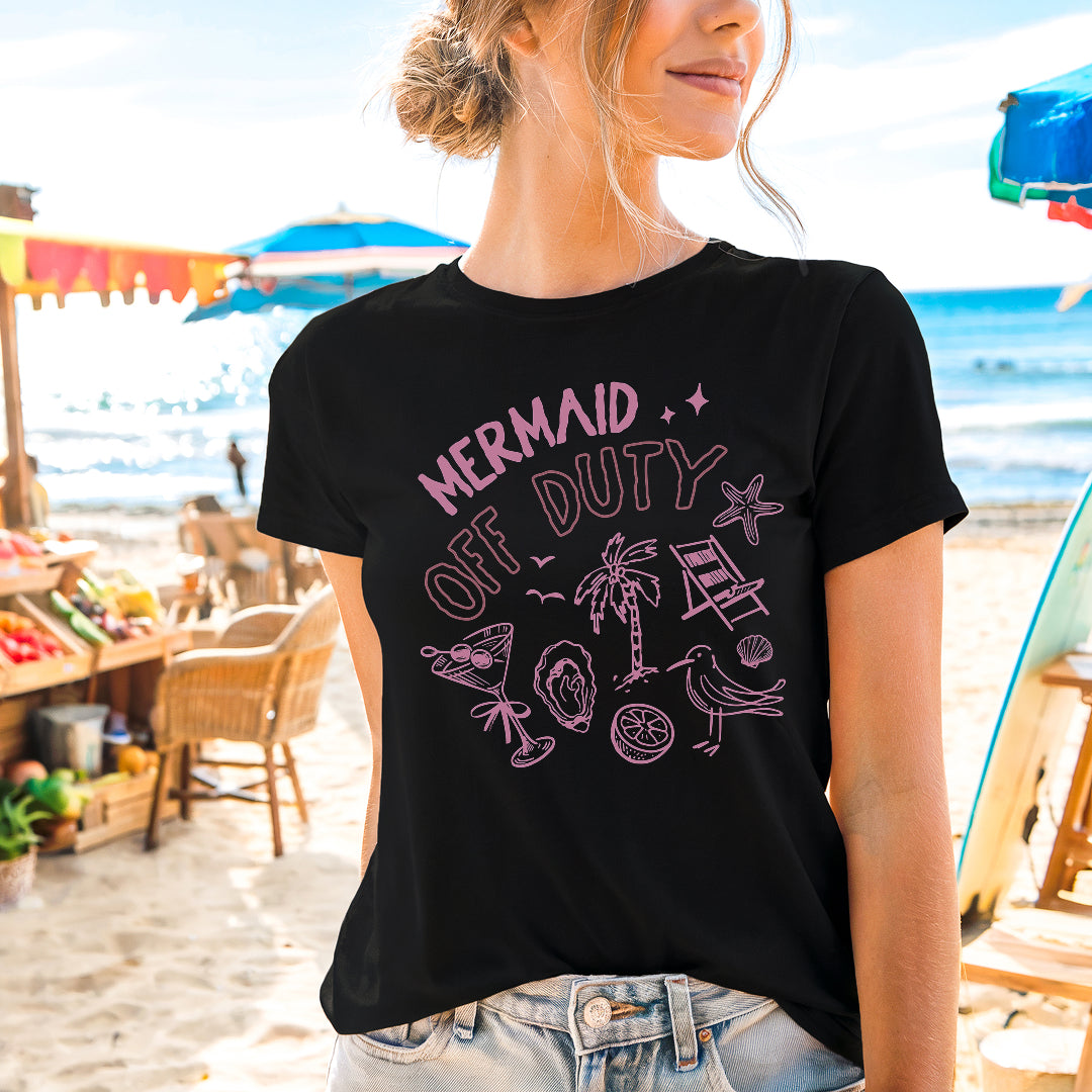 a woman standing on the beach wearing a mermaid of duty shirt