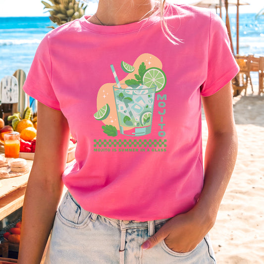 a woman standing on a beach wearing a pink shirt
