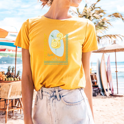 a woman standing on a beach wearing a yellow shirt