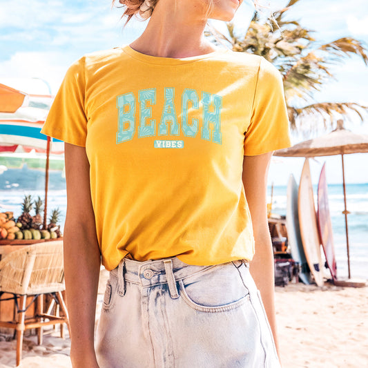 a woman standing on a beach wearing a yellow shirt