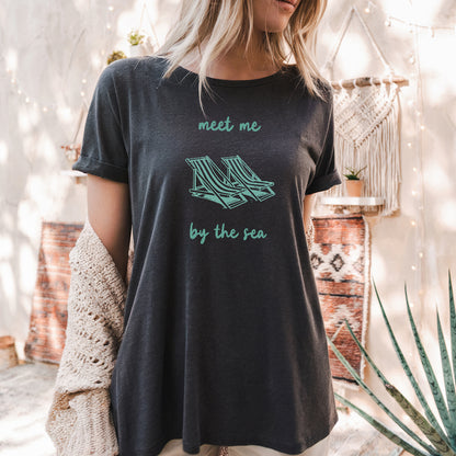 a woman wearing a t - shirt that says meet me by the tea