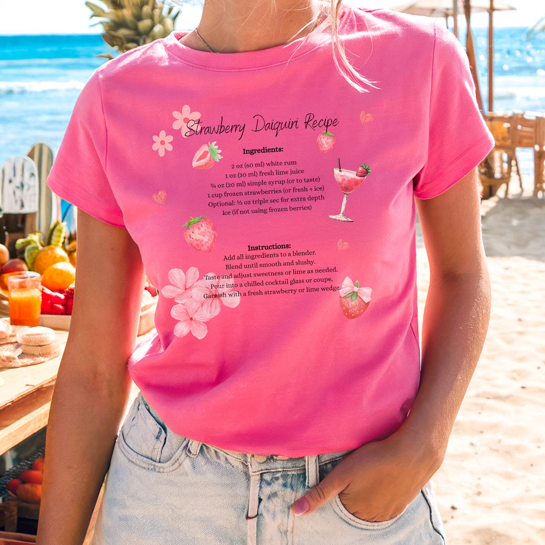 a woman standing on a beach wearing a pink shirt