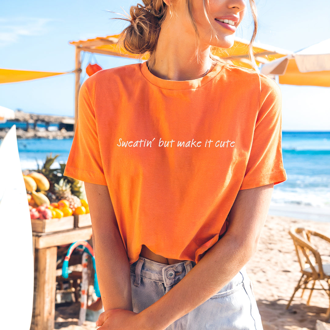 a woman in an orange shirt standing on a beach