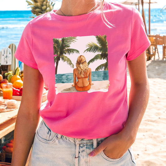 a woman wearing a pink shirt with a picture of a woman sitting on the beach