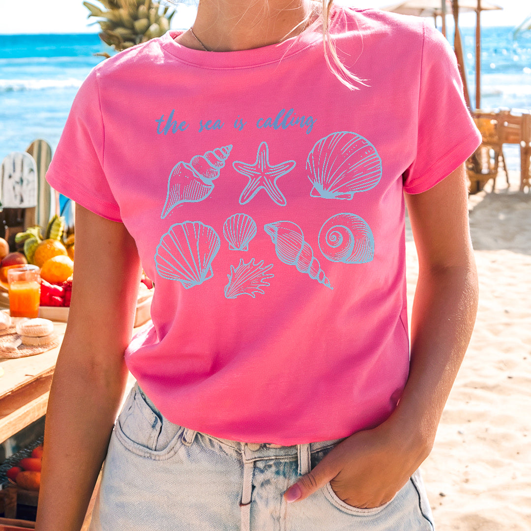 a woman wearing a pink shirt with shells on it